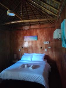 a bedroom with a large bed with white sheets at The Garden Tropical Cabins in Basdiot