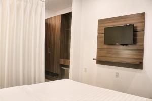 a bedroom with a bed and a tv on a wall at Khách Sạn Nhơn Lý LYS HOTEL in Quy Nhon