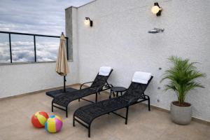 three chairs and an umbrella on a patio with volleyballs at PISCINA, 2qts, 2 banh, varanda c churrasqueira, estacionamento, elevador, portaria in São Lourenço