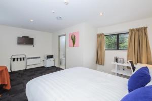 a bedroom with a large white bed and a window at Greenlane Motel in Auckland