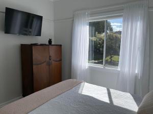 a bedroom with a bed and a dresser and a window at Moruya Heads Constable Street in Moruya Heads