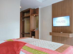 a bedroom with a bed and a flat screen tv at Hotel Indria in Bukittinggi