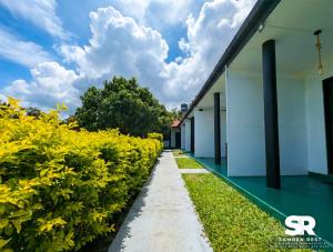 a walkway in front of a building with yellow flowers at Samren Rest in Hambantota