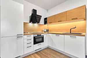 a kitchen with white cabinets and a tv on the wall at Apartmány BD Boží Dar by Mountain ways in Boží Dar