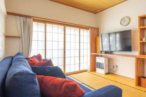 a living room with a blue couch and a large window at Vaisala in Nozawa Onsen