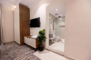 a bathroom with a toilet and a tv on the wall at Rewaq Resident رواق ريزدنت in Medina +49 photos