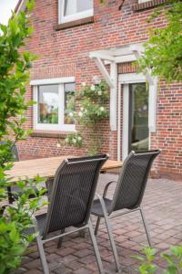 two chairs and a wooden table in front of a brick building at Birgits Huuske in Stedesdorf