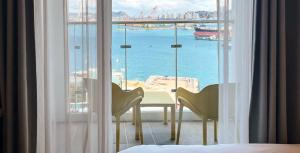 a bedroom with a table and chairs and a view of the ocean at Busan CONNECT Ocean Hotel in Busan