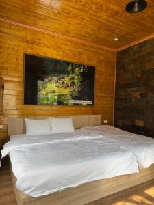a bedroom with a large bed with a tv on the wall at Mộc Sơn Homestay in Mộc Châu