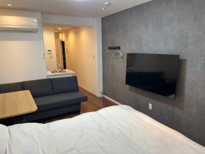 a bedroom with a couch and a flat screen tv at Eko House in 横浜石川町駅 in Yokohama