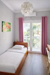 a bedroom with a bed and a window with pink curtains at Hotel Europa - Family and Senior Friendly in Kavála
