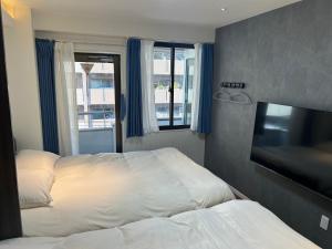 a hotel room with two beds and a flat screen tv at Eko House in 横浜石川町駅 in Yokohama