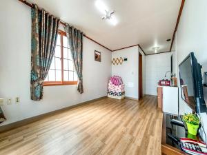 a living room with wooden floors and a tv at Sea Dragon Pension in Seogwipo