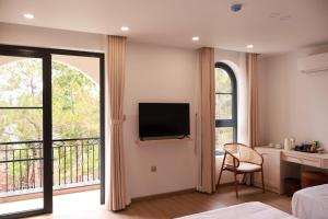 a room with a bed and a tv and a balcony at Veluna Hotel Mang Den in Kon Tum (2)
