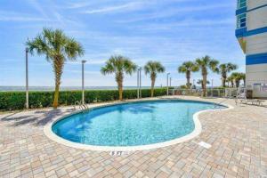 a swimming pool with palm trees and a building at Carolinian Resort 2032 in Myrtle Beach