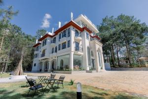a large white building with chairs in front of it at Veluna Hotel Mang Den in Kon Tum (2)