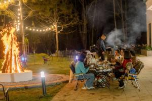 a group of people sitting at tables in front of a fire at Veluna Hotel Mang Den in Kon Tum (2)
