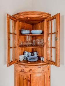 a wooden cabinet with plates and dishes in it at Sea You Soon in Callantsoog