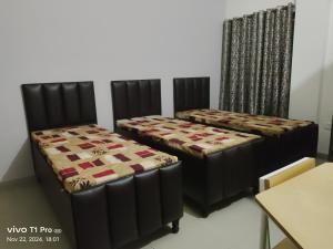 two beds sitting in a room with a table at Homely Space PG in Noida +1 photo