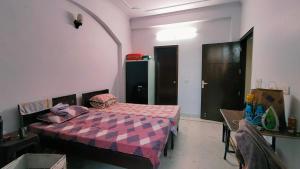 a bedroom with a bed and a table and a door at Homely Space PG in Noida