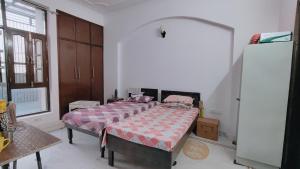 a bedroom with two beds and a refrigerator at Homely Space PG in Noida