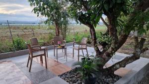 a patio with chairs and a table under a tree at Pool of Siloam with tiny house in Bangad