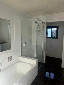a white bathroom with a shower and a tub at Albury Central Hideaway at Somerby in Albury +21 photos