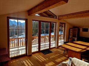 a living room with a table and large windows at Faschingalm Loft in Lienz