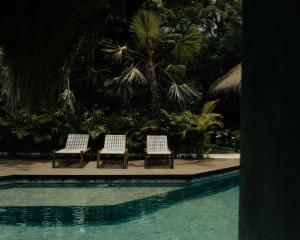 three chairs sitting next to a swimming pool at RONJA Boutique Hotel - Adults Only in Uluwatu