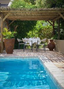 a table and chairs under a pergola next to a pool at Kokon Boutique Guesthouse in Somerset West