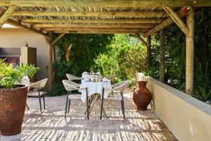 a table and chairs under a wooden pergola at Kokon Boutique Guesthouse in Somerset West