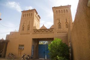 un bâtiment avec deux tours et une porte bleue dans l'établissement Gite Kasbah La Palmeraie, à Skoura