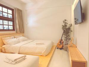 a bedroom with two beds and a guitar in it at Jellyfish Hostel in Jomtien Beach