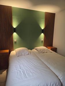 a bedroom with a large white bed with a green wall at Hotel-Restaurant La Crémaillère in Jalhay