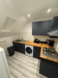 a kitchen with black cabinets and a sink and a stove at Whitford living 2 in Jarrow