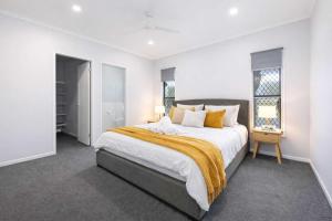a white bedroom with a large bed and two windows at 4BR Family Home w Golf Course Views, BBQ & Secure Parking in Rosslea