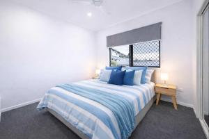 a bedroom with a bed with blue pillows and a window at 4BR Family Home w Golf Course Views, BBQ & Secure Parking in Rosslea +6 photos