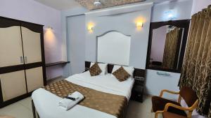 a small room with two beds and a chair at Hotel Aishwarya in Pandharpur