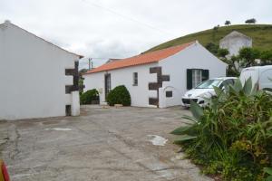 a white house with a car parked in a parking lot at TINA 3B - Alojamento Local - RRAL 760 in Porto Martins