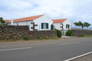 a house on the side of a road with a stone wall at TINA 3B - Alojamento Local - RRAL 760 in Porto Martins +4 photos