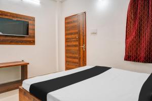 a bedroom with a bed and a tv and a door at Super Hotel O Neelbad Guest House in Bhopal
