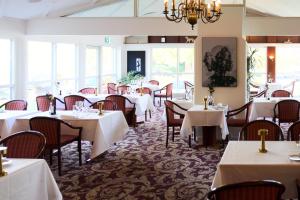 a dining room with white tables and chairs at Montra Odder Parkhotel in Odder