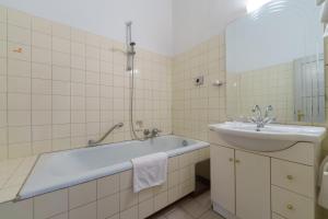 ein Badezimmer mit Badewanne und Waschbecken in der Unterkunft Altstadthotel Eck in Lienz + 38 Fotos