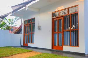 a white house with wooden doors and windows at Anula Villa in Ahangama +11 photos