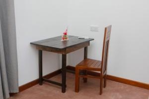 a wooden table with a chair next to a refrigerator at Anula Villa in Ahangama