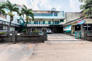 a building with palm trees in front of a street at Urbanview Hotel Bartu Moh Toha Bandung by RedDoorz in Bandung