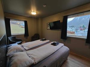 a bedroom with a large bed and two windows at Gjøa Motell in Rosendal
