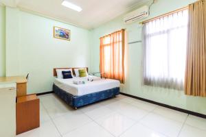 a bedroom with a bed with a sink and a window at Urbanview Hotel Bartu Moh Toha Bandung by RedDoorz in Bandung