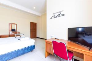 a bedroom with a desk and a bed and a television at Urbanview Hotel Bartu Moh Toha Bandung by RedDoorz in Bandung