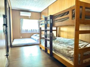 two bunk beds in a room with wooden walls at 海輪邸 in Shima